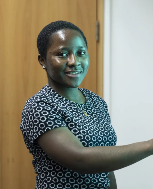 A female student in a patterned dress smiles while using a touchscreen in a classroom. The screen displays words related to the months and seasons. A female student in a patterned dress smiles while using a touchscreen in a classroom. The screen displays words related to the months and seasons.